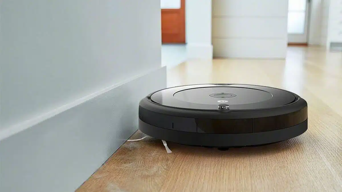 Aspirateur robot noir en fonctionnement sur un parquet clair