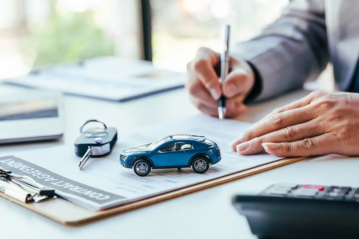 Signature d'un contrat, avec des clés et une petite voiture bleue